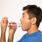 Man using metered-dose inhaler with spacer.