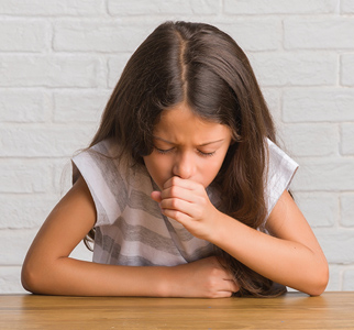 Young girl with her head lowered, coughing